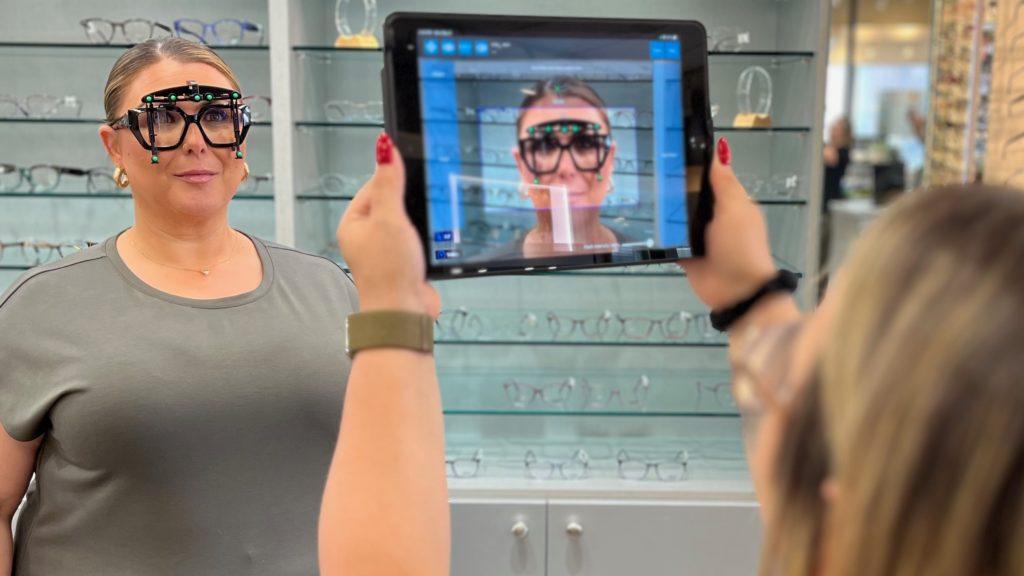 A woman with Optikam glasses on her face having her picture taken on an ipad.